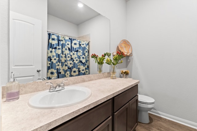 bathroom featuring vanity with extensive cabinet space, toilet, and hardwood / wood-style floors