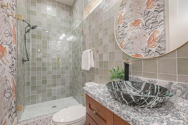 bathroom with walk in shower, vanity, tile walls, and toilet