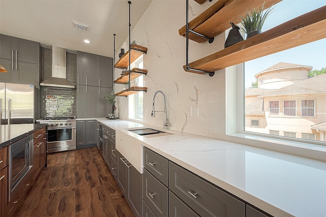 kitchen with decorative backsplash, high quality appliances, wall chimney range hood, and sink