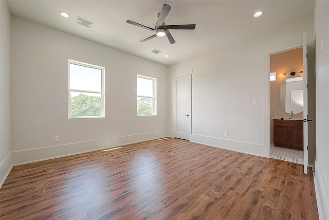 unfurnished bedroom featuring ceiling fan, wood-type flooring, and ensuite bath