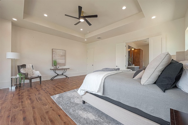 bedroom featuring hardwood / wood-style flooring, ceiling fan, and a tray ceiling