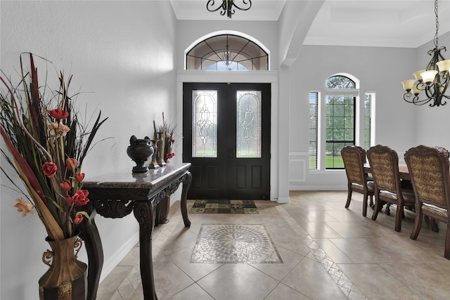 entryway featuring a notable chandelier, ornamental molding, and light tile patterned floors