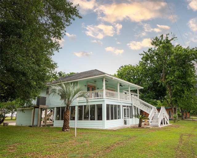 rear view of property featuring a yard, a balcony, ceiling fan, and a sunroom