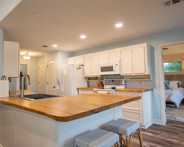 kitchen with kitchen peninsula, sink, white cabinets, and white appliances