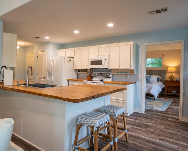 kitchen featuring dark hardwood / wood-style flooring, white appliances, sink, white cabinetry, and butcher block counters