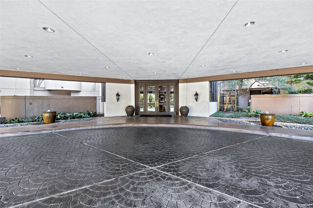 interior space with a textured ceiling and french doors