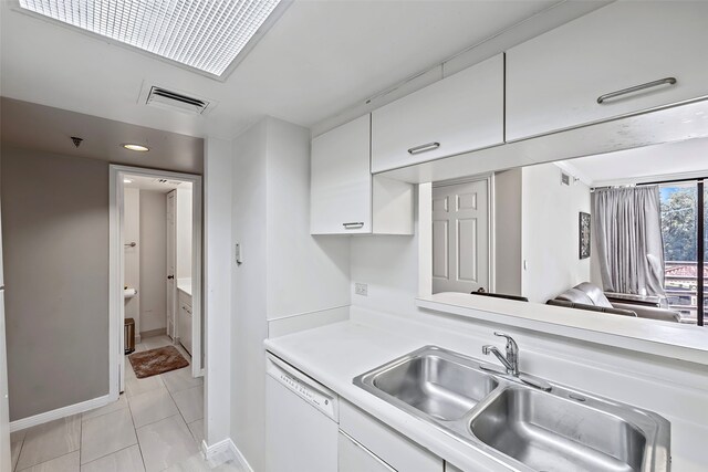 kitchen with sink, light tile flooring, dishwasher, and white cabinetry