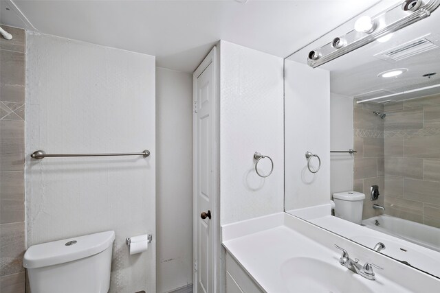 full bathroom with vanity with extensive cabinet space, toilet, and tiled shower / bath