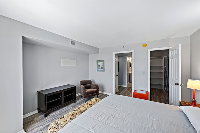 bedroom with a closet, dark wood-type flooring, and a spacious closet