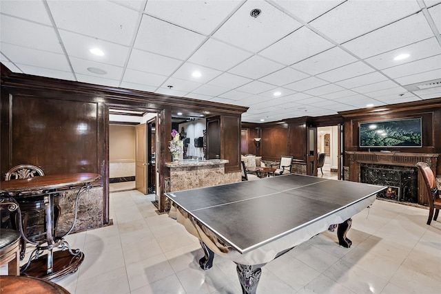 rec room with a paneled ceiling, light tile flooring, and a fireplace