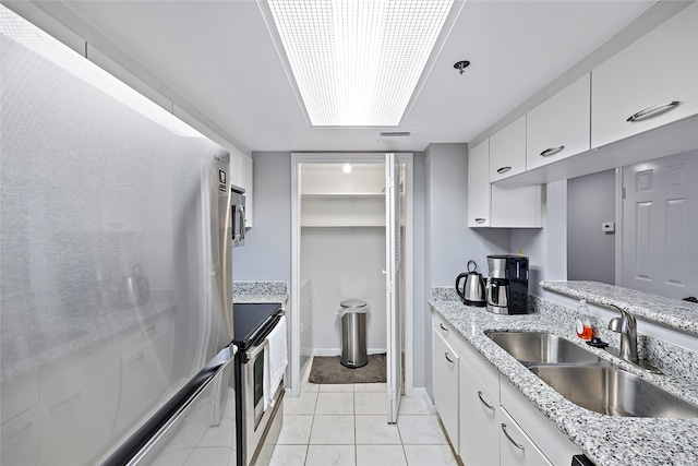 kitchen featuring stove, white cabinetry, white fridge, sink, and light tile floors