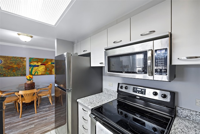 kitchen with stainless steel appliances, light stone countertops, light wood-type flooring, and white cabinetry