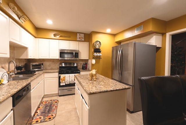 kitchen featuring a center island, appliances with stainless steel finishes, white cabinets, and light tile floors