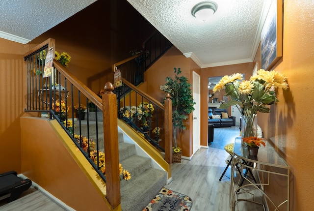 staircase featuring hardwood / wood-style flooring, crown molding, and a textured ceiling