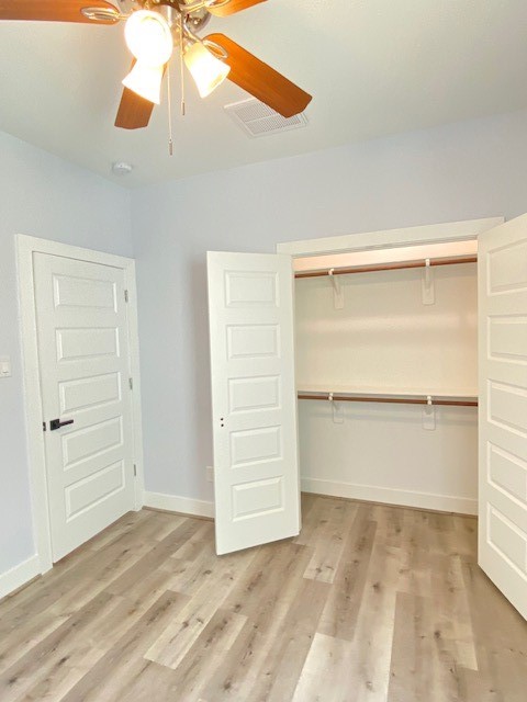 unfurnished bedroom with ceiling fan, a closet, and light wood-type flooring