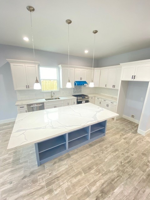 kitchen featuring pendant lighting, a center island, white cabinets, and stainless steel appliances