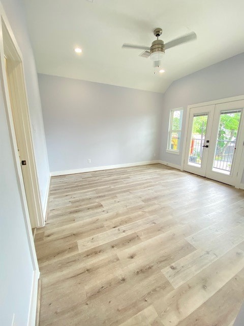 empty room featuring french doors, light wood-type flooring, ceiling fan, and lofted ceiling