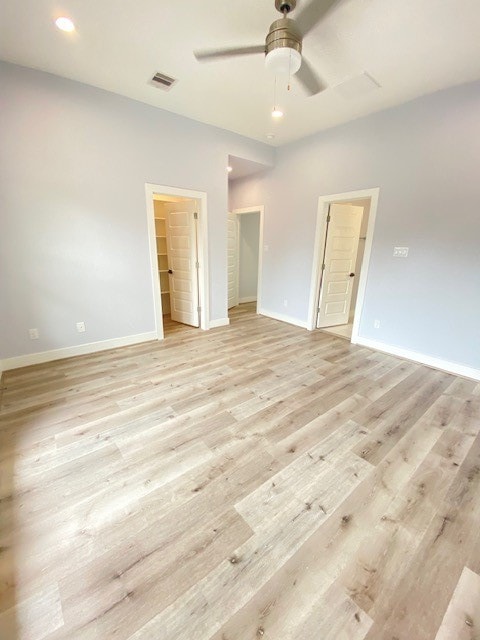 unfurnished bedroom with ceiling fan, a spacious closet, and light hardwood / wood-style flooring