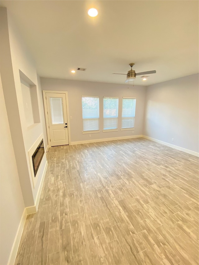 unfurnished living room featuring ceiling fan and light wood-type flooring