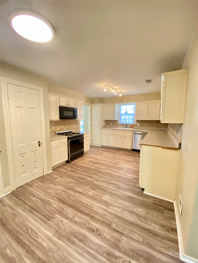 kitchen featuring tasteful backsplash, sink, black appliances, light hardwood / wood-style flooring, and white cabinetry