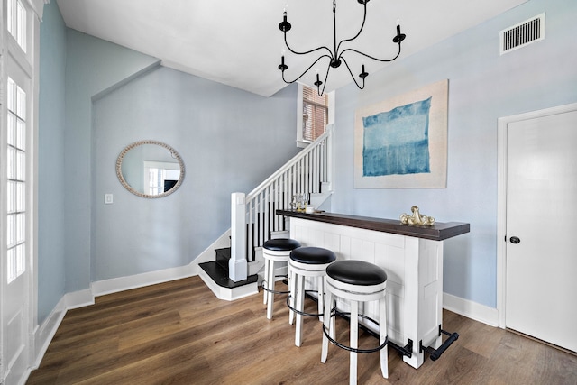 bar with a healthy amount of sunlight, dark hardwood / wood-style floors, pendant lighting, and a notable chandelier