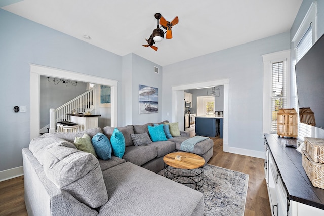 living room with ceiling fan with notable chandelier and dark hardwood / wood-style floors