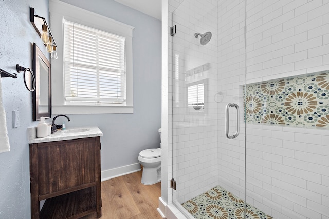 bathroom with wood-type flooring, vanity, toilet, and walk in shower