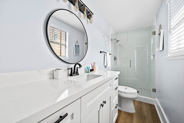 bathroom with a shower with shower door, wood-type flooring, vanity, and toilet