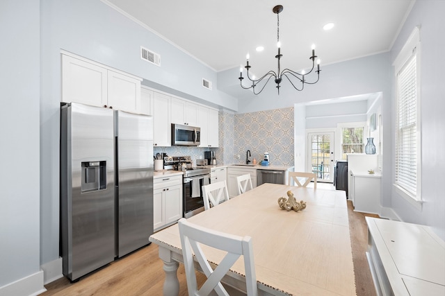 kitchen featuring appliances with stainless steel finishes, a notable chandelier, backsplash, and white cabinets