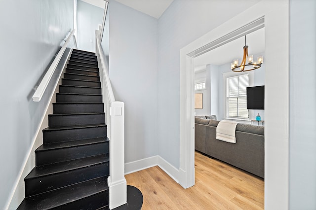 stairway featuring light hardwood / wood-style floors and an inviting chandelier