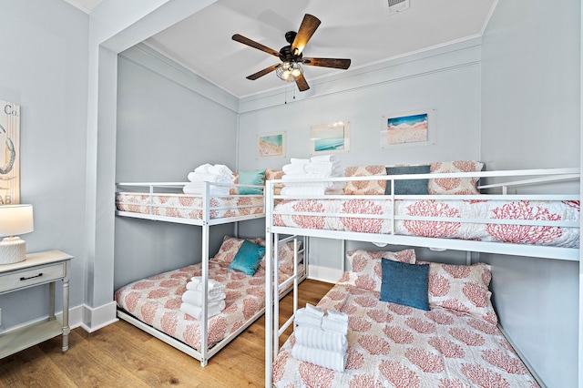 bedroom with hardwood / wood-style floors, ceiling fan, and crown molding