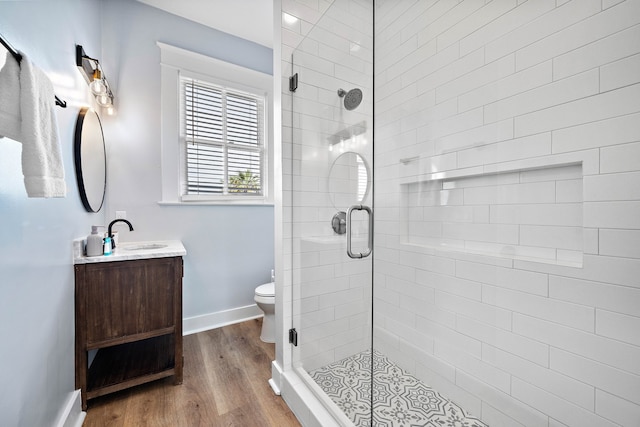 bathroom with wood-type flooring, vanity, toilet, and walk in shower