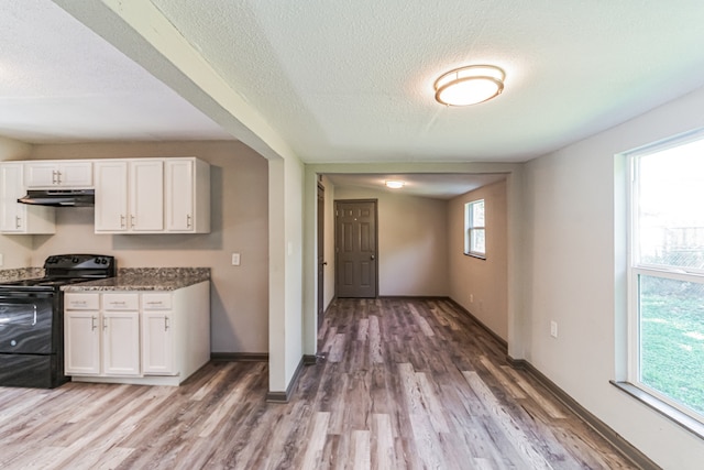 kitchen featuring wood-type flooring, black range with electric stovetop, and white cabinetry