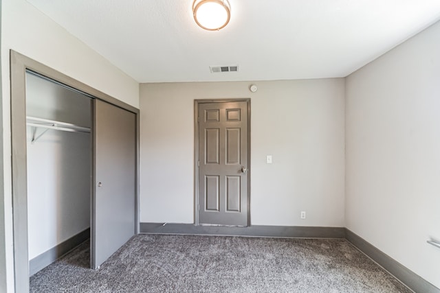 unfurnished bedroom featuring dark colored carpet and a closet