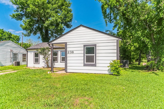 rear view of house featuring central AC and a yard