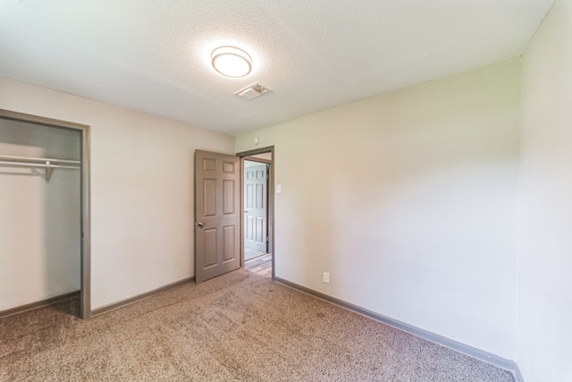 unfurnished bedroom with a closet, a textured ceiling, and carpet flooring