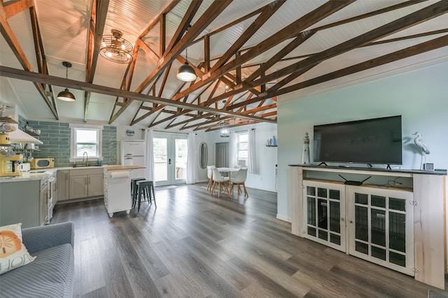 unfurnished living room with sink, dark hardwood / wood-style flooring, vaulted ceiling with beams, and french doors