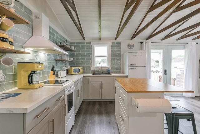 kitchen with backsplash, white appliances, lofted ceiling with beams, wall chimney exhaust hood, and sink