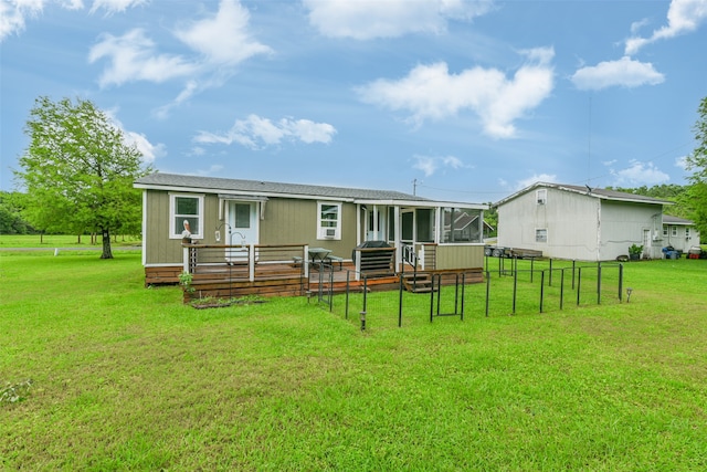 rear view of house featuring a deck, a yard, and a sunroom