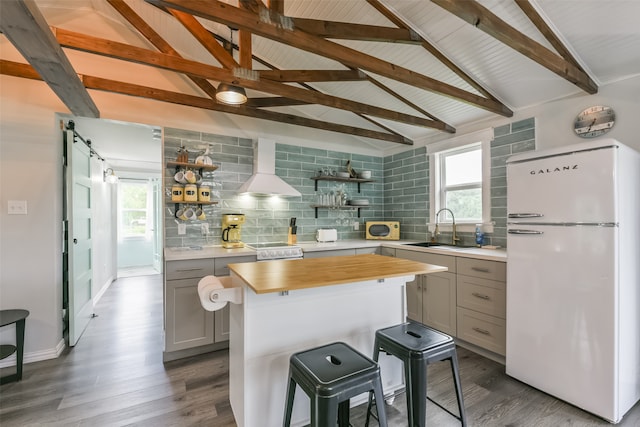 kitchen featuring gray cabinets, white appliances, tasteful backsplash, hardwood / wood-style flooring, and wall chimney exhaust hood