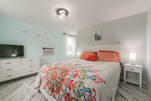 bedroom with a wall mounted AC and light hardwood / wood-style floors