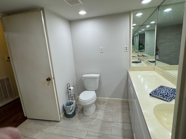 bathroom featuring vanity with extensive cabinet space, double sink, wood-type flooring, and toilet