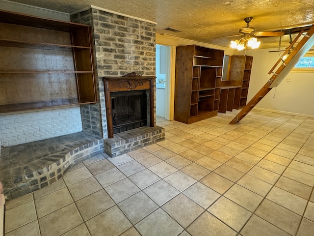 unfurnished living room with ceiling fan, a brick fireplace, light tile floors, a textured ceiling, and brick wall