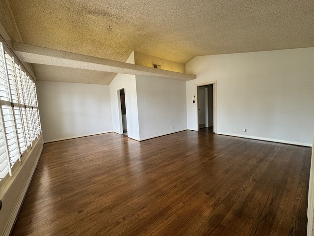 spare room with a textured ceiling, dark hardwood / wood-style floors, and vaulted ceiling