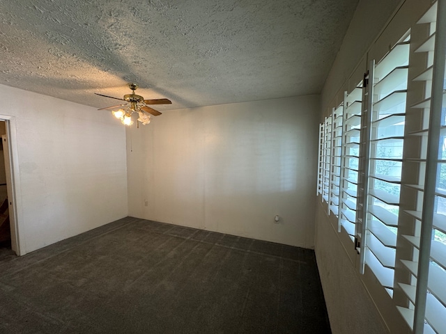 unfurnished room with ceiling fan, dark carpet, and a textured ceiling