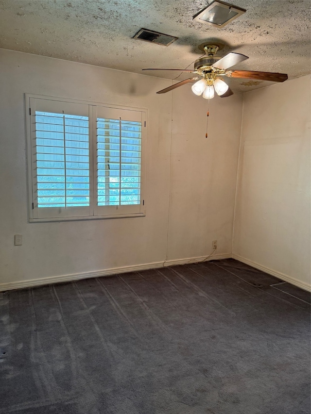 spare room with ceiling fan, dark carpet, and a textured ceiling