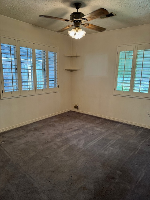 spare room with dark colored carpet, ceiling fan, and a textured ceiling