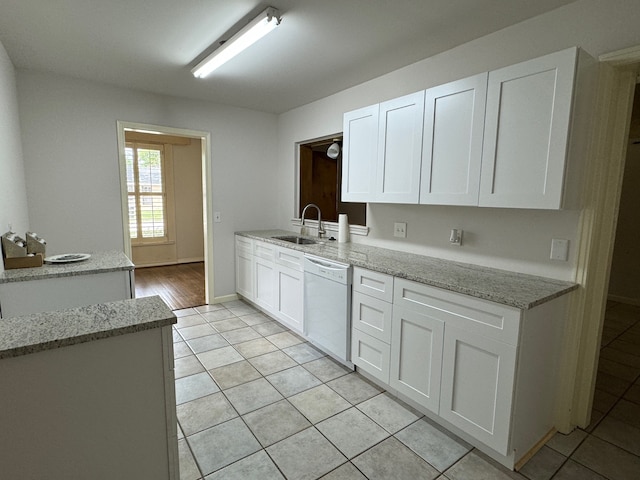 kitchen with light stone countertops, dishwasher, white cabinetry, and light tile flooring