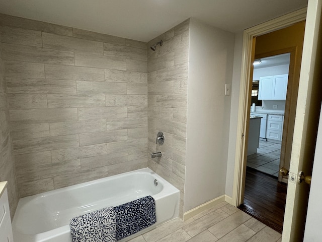 bathroom with hardwood / wood-style floors, tiled shower / bath, and vanity