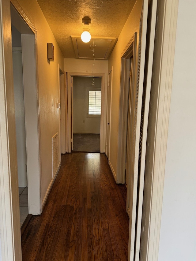 hallway with dark hardwood / wood-style flooring and a textured ceiling